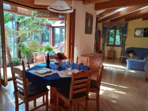 Gedeckter Esstisch, Wohnzimmer und Wintergarten eines Niedrigenergiehauses mit Smart Home Steuerung